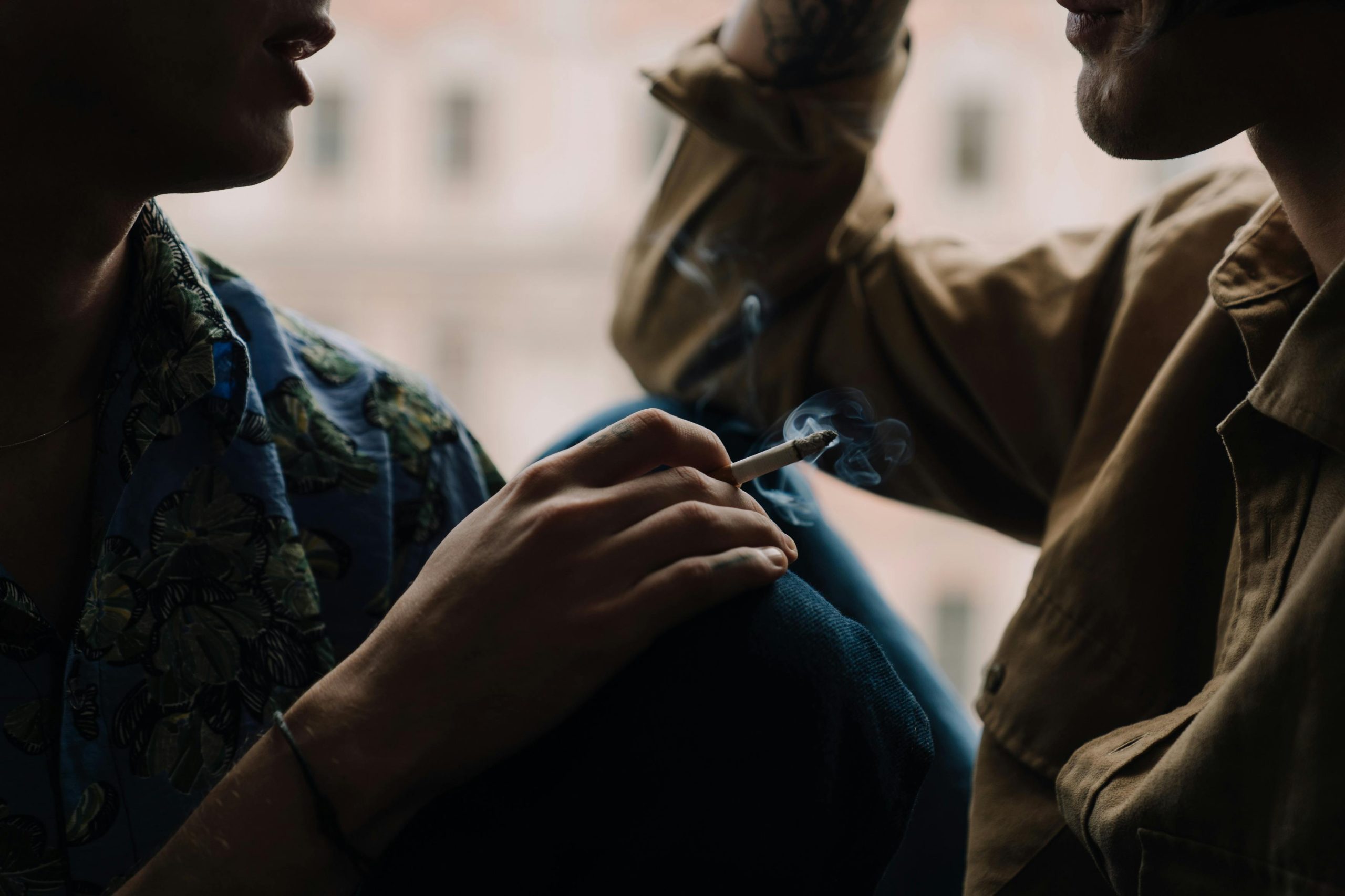 Intimate conversation between two individuals, with smoke rising from a cigarette.