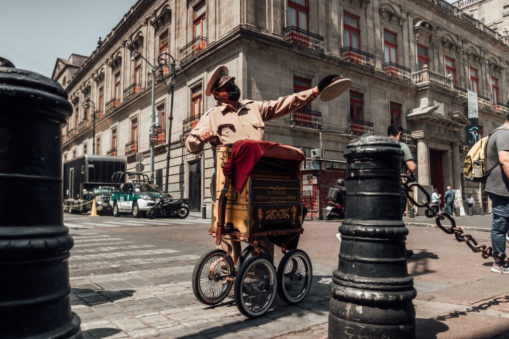 A whimsical street performer entertains in Mexico City's historic center with vibrant architecture.