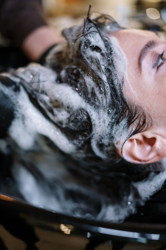 pexels photo 3993454 3993454 Close-up of a woman getting her hair washed at a salon, covered in shampoo foam.