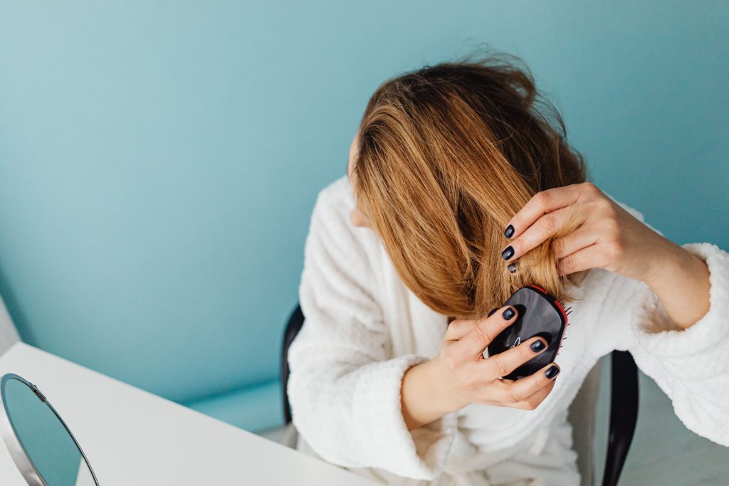 pexels photo 7321234 7321234 A woman in a bathrobe combs her hair reflecting self-care and relaxation.