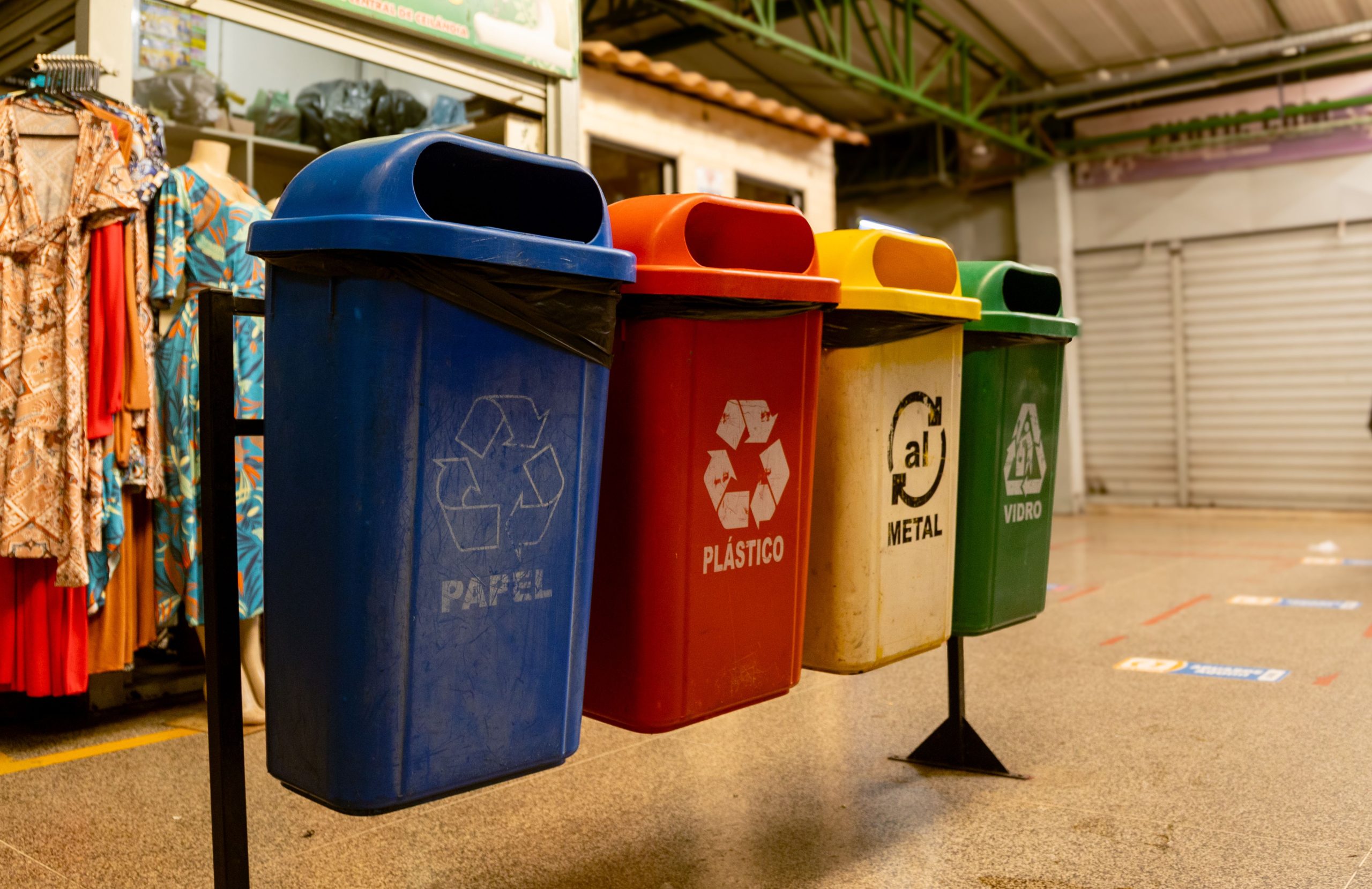 El reto post-partido: la realidad detrás del "triangulito del reciclaje" en los envases plásticos Four recycling bins for paper, plastic, metal, and glass indoors.