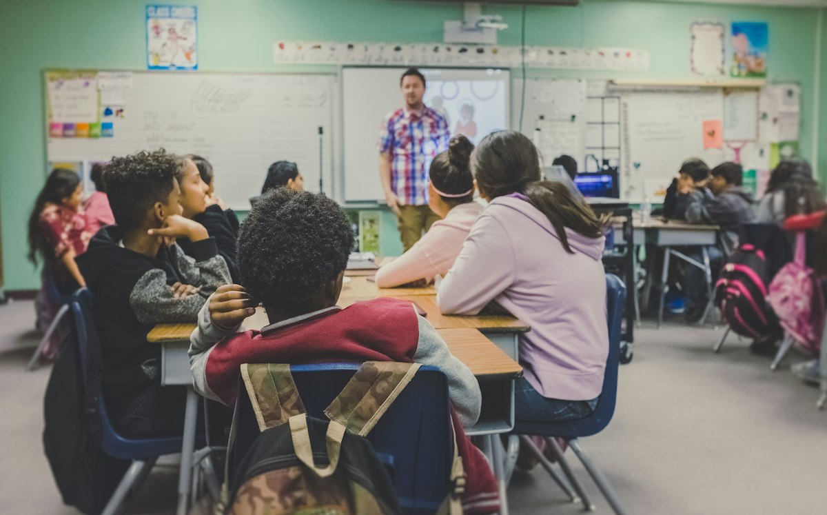 Tecnología en las aulas y salud mental juvenil: El 73% respalda restringir redes sociales a menores mientras avala la IA en escuelas Estudiantes en aula escolar interactuando con herramientas pedagogicas y tecnologia